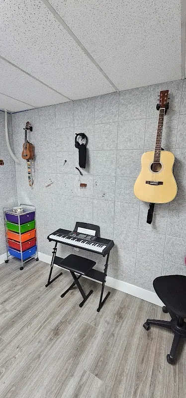 Music therapy corner with an electric keyboard on a stand, two acoustic guitars hanging on the wall, and a small rolling cart with rainbow drawers for supplies